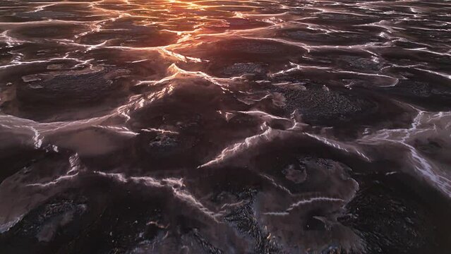 Drone dolly on black mound textured pattern of polluted landscape with braided streams between piles