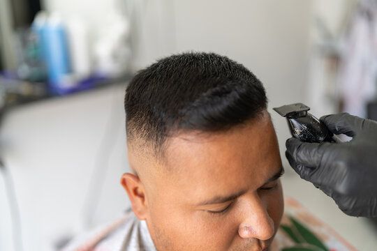 Barber shaping the haircut of a client using electric razor