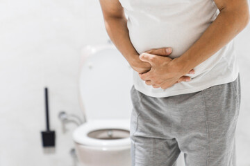 Men have stomachache and use their hands to hold their stomach In the bathroom. Constipation or colon cancer. diarrhea and severely toxic food. Man touch belly in the bathroom. Abdominal pain - obrazy, fototapety, plakaty