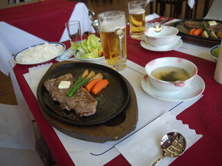 Japanese lunch set two persons with sirloin steak served on iron pan, miso soup, vegetable salad and beer 