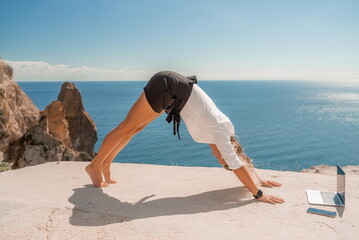 Freelance women sea working on the computer. Good looking middle aged woman typing on a laptop keyboard outdoors with a beautiful sea view. The concept of remote work.