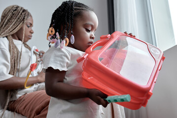 little awesome black kid holding red bag, playing doctor, role game. close up side view shot