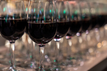 Wine glasses filled with red wine arranged and presented on a table top for self-service by party...