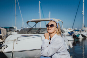 Woman in white shirt in marina , surrounded by several other boats. The marina is filled with boats of various sizes, creating a lively and picturesque atmosphere.