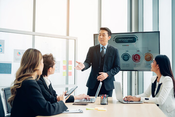 Male mature caucasian ceo businessman leader with diverse coworkers team, executive managers group at meeting. Multicultural professional businesspeople working together on research plan in boardroom.