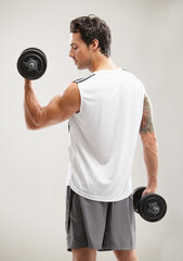 Fitness, back or athlete in dumbbell workout or training for wellness in studio on grey background. Strong man, model or bodybuilding exercise for power, body challenge or weights with bicep curls