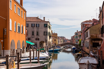 Fototapeta na wymiar Scenic view of peaceful canal Vena nestled in charming town of Chioggia, Venetian Lagoon, Veneto, Italy. Small boats floating in calm water. Enchanting reflections create atmosphere of tranquility