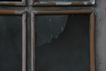 Broken, vintage, aged old vintage brown painted wooden window. broken glass. cracked glass entrance door. exterior background.