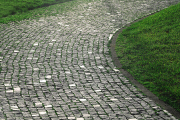 Cobblestone path s-curve. Cobbled stone path in summer park. stoned path in the meadow. green grass around.