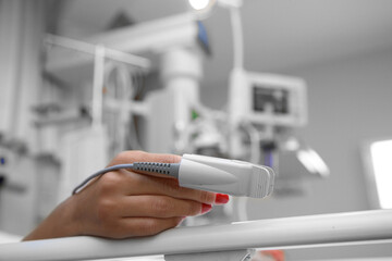 close-up of oxygen meter on patient finger lying in hospital patient room