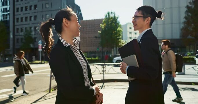 Asian people in city, professional and bow for greeting with conversation, travel and commute to work in morning. Business man, woman and hello in Tokyo, journey and urban street with communication
