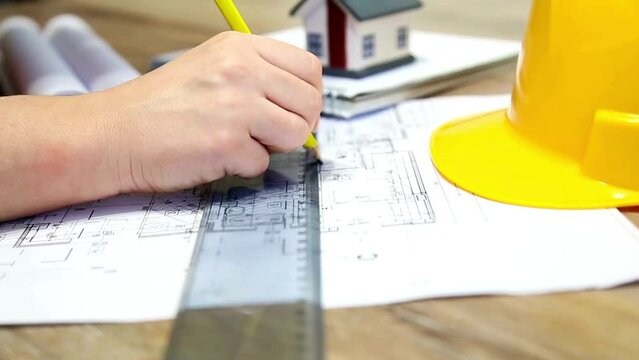 Close-up of an architect drawing and measuring construction plan in the office. Architect male project drawing close-up. paperwork of floor plan for building, development or planning property.