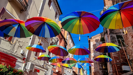 Gorgeous bursts of colors from a vibrant assortment of umbrellas embellishing the clear blue sky in...