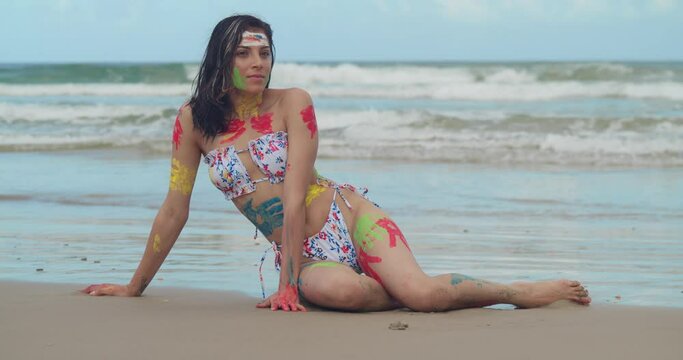 A sunny Caribbean beach showcased the beauty of a young girl in a bikini, her body adorned with an array of vibrant paint.