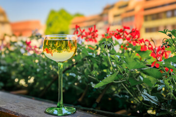 A glass of Gewurztraminer wine at an outdoor restaurant, blurred half timbered houses and flowers...