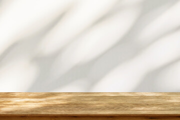 Empty wood table top on beige wall texture with tree leaves shadow background