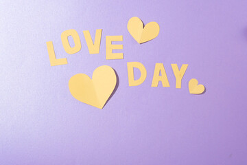 LOVE DAY lettering and paper hearts on a soft pastel background. Ideal for anniversary ads. Top view, flat lay, with ample copy space. Create a romantic ambiance.