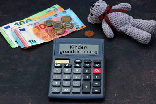 Kindergrundsicherung: Teddyb&auml;r mit Euro Banknoten und dem Text Kindergrundsicherung auf dem Display eines Taschenrechners.