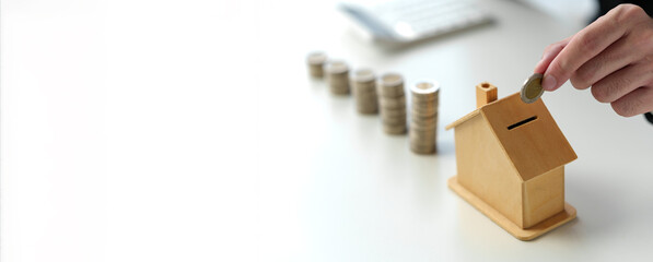 Businessman inserts coins into piggy bank to manage money and savings plan, adding value, idea of...