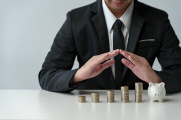 Businessman uses hands to protect stack of coins, perspective view of protection, planning, saving money for expenses. Saving for the future.