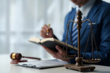 Lawyer, legal advisor, businessman reading and using pen pointing at legal code information Business terms on books working with scales and hammers in office.
