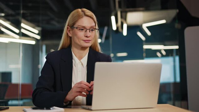 Proud, happy, successful motivated employee business woman typing on a laptop and looking at the camera in her office. Portrait of a young female entrepreneur writing a project smiling in workplace.