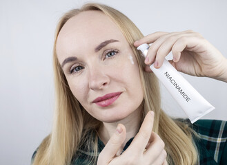 Vitamin A, Retinol, Niacinamide, Vitamin C. Girl smears her face with antioxidant anti-wrinkle...