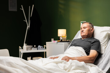 An elderly man lies in a hospital bed gathering strength for a speedy recovery.