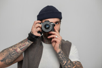 Handsome professional hipster man photographer holding mirrorless photo camera and taking photos in...