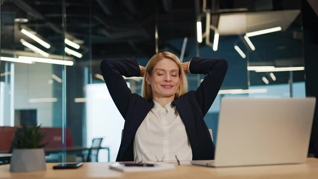 Happy satisfied caucasian business woman relax sit at office desk finished laptop pc work put hands behind head feel satisfied with work well done stress relief peace of mind concept chill at work.