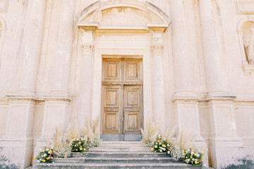 Fototapeta na wymiar Bouquets of flowers stand on the steps of an ancient church
