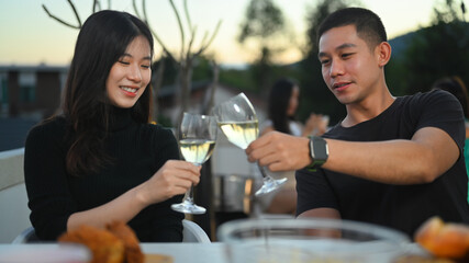 Shot of young Asian couple toasting champagne and enjoying lunch together at a rooftop restaurant.