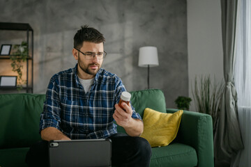 One man hold medicine drugs bottle pills read label on digital tablet