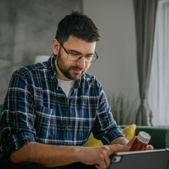 One man hold medicine drugs bottle pills read label on digital tablet