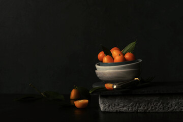 Stillleben mit Kumquats vor dunklem Hintergrund - 703186438