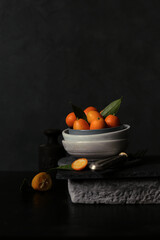 Stillleben mit Kumquats vor dunklem Hintergrund - 703186497