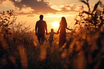 Fotobehang A beautiful scene of a family walking through a field at sunset. Perfect for nature, family, and outdoor lifestyle themes © Fotograf