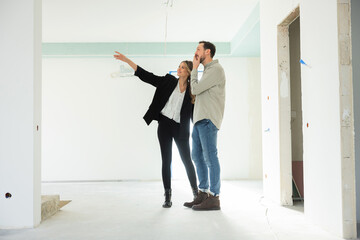 Fototapeta premium Happy ownerships owners of a new house delighted wife and husband observing examining new house discussing all furniture.