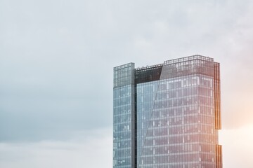 High-rise office building. A modern glass building stands tall against a cloudy sky showcasing...