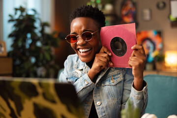 Beautiful delighted afro american black wman in pink sunglasses sitting in the cozy living room...