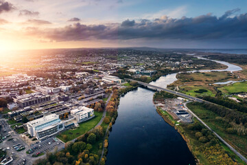 Aerial view on Galway city suburbs and river Corrib at sunset. Dramatic rich cloudy sky. Town high...