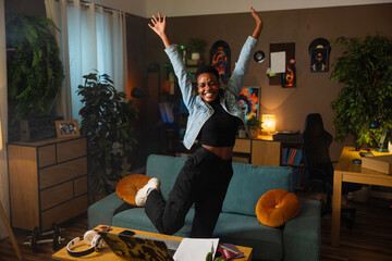 Happy afro american dark skinned woman jumping in the living room happy girl are accepted to the...