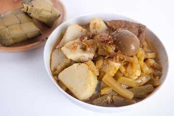 Ketupat Sayur or Lontong Sayur, a typical Indonesian food. Served with pumpkin vegetables, boiled eggs and tofu stew and crackers. Served during Ramadan, Eid al-Fitr and Adha. White Background