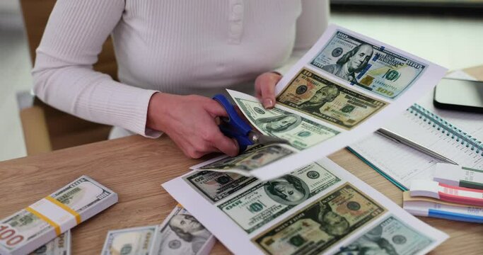 Closeup of woman cutting out printed American dollars