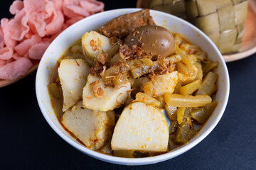 Ketupat Sayur or Lontong Sayur, a typical Indonesian food. Served with pumpkin vegetables, boiled eggs and tofu stew and crackers. Served during Ramadan, Eid al-Fitr and Adha. Black Background