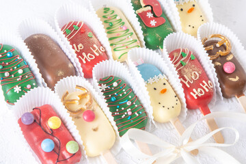 Christmas dessert. Sweet food. Cheesecake on a stick in the shape of ice cream. Children's treat in winter. Candy Christmas tree, snowman, deer and Santa Claus. Gingerbread cookies background.