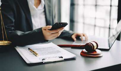 justice and law concept. Male judge in a courtroom the gavel, working with smart phone and laptop...