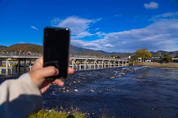 Poster A smartphone shooting Togetsukyo bridge near Katsuragawa river in Kyoto in autumn © tokyovisionaryroom
