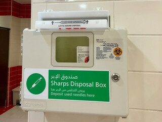 Safe medical needle disposal container on a toilet wall in the Dubai airport. 