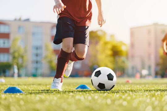 Soccer player on field with ball. Close up of boy kicking soccer ball. Slalom drill during a football training session